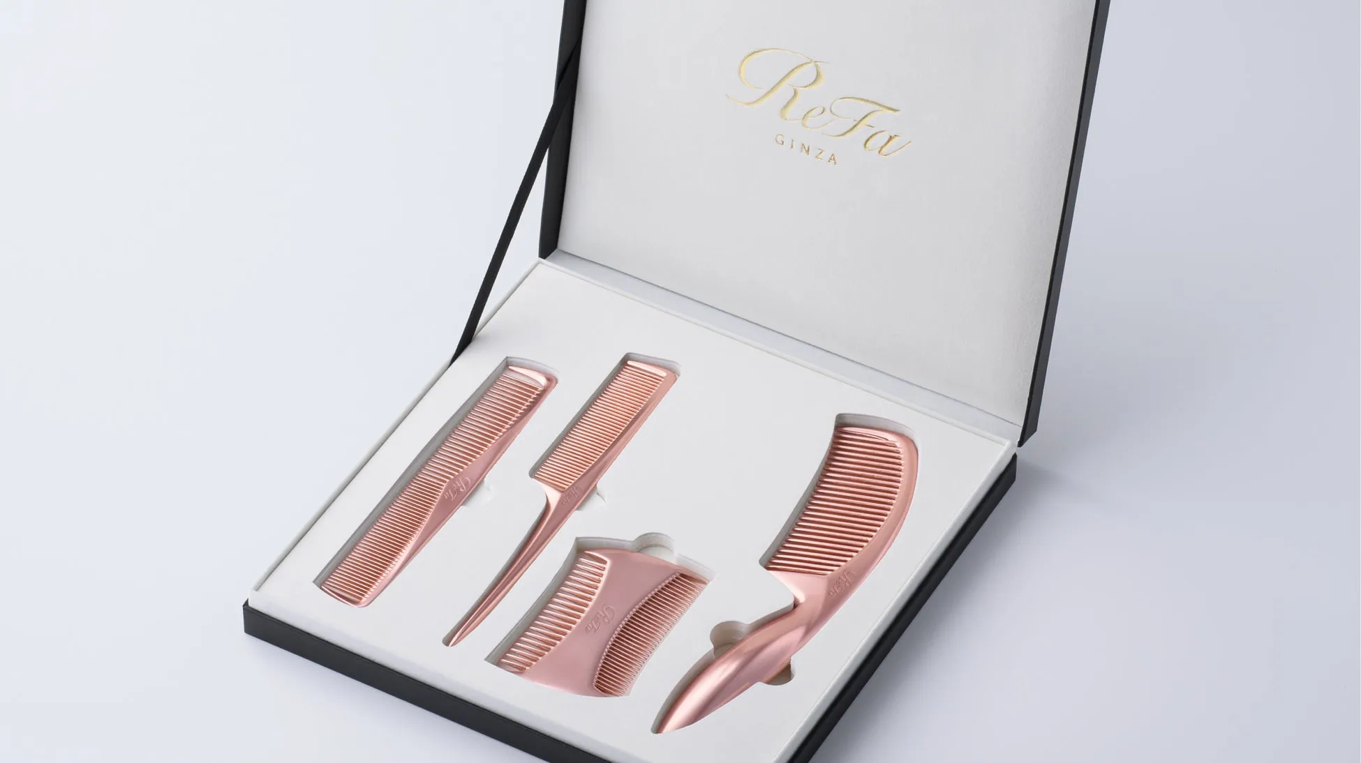 ReFaの櫛のセットが、高級感のある黒い箱に収められています。櫛はピンクゴールドの色合いで、様々な形状をしています。