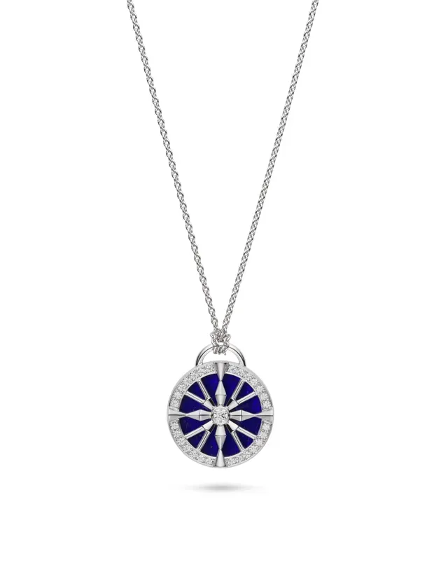 白い背景に、円形のペンダントが付いた銀色のネックレスの写真です。ペンダントは、青い中心部、ダイヤモンドで縁取られた外側のリング、ダイヤモンドで飾られた放射状のデザインが特徴です。