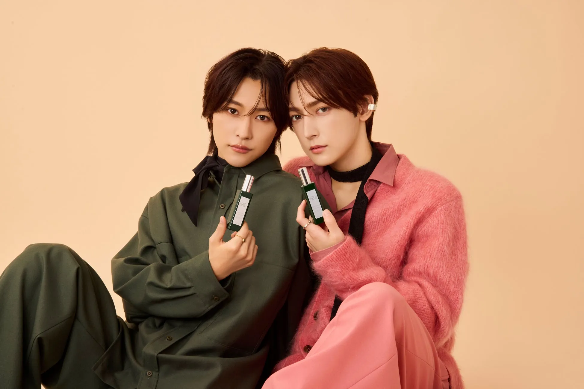 男性二人が香水ボトルを持ってポーズをとっている写真