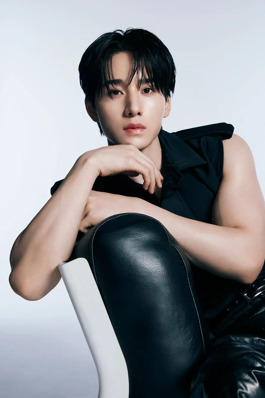 黒いノースリーブのシャツと革のズボンを着て、椅子に寄りかかっている男性のクローズアップ写真。