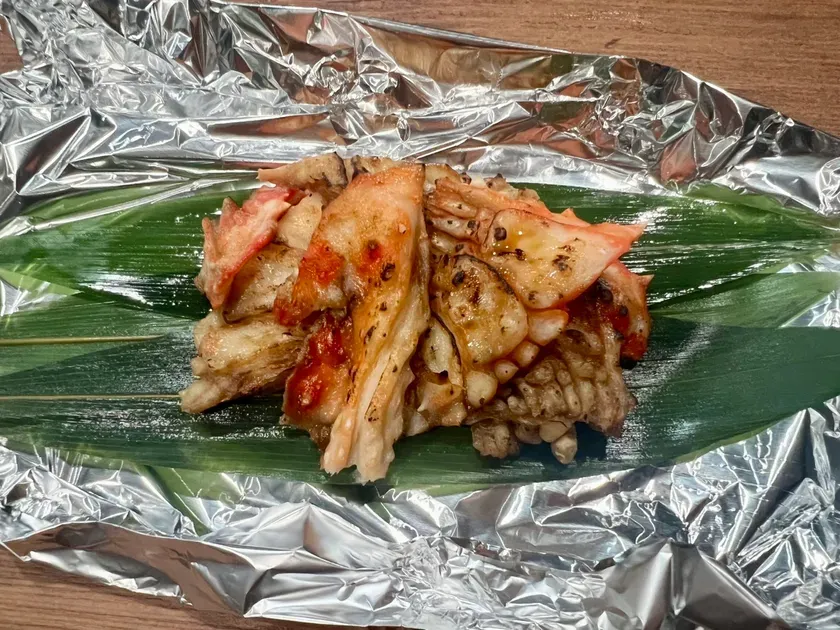 アルミホイルと葉の上に置かれた、調理されたカニのクローズアップです。