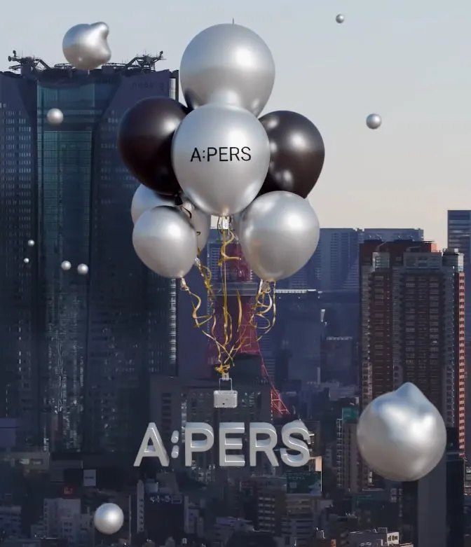 都市の上空に浮かぶ風船の画像。風船は黒と銀色で、A:PERSの文字が印字されている。背景には高層ビルが立ち並び、全体的に近未来的な印象を与える。