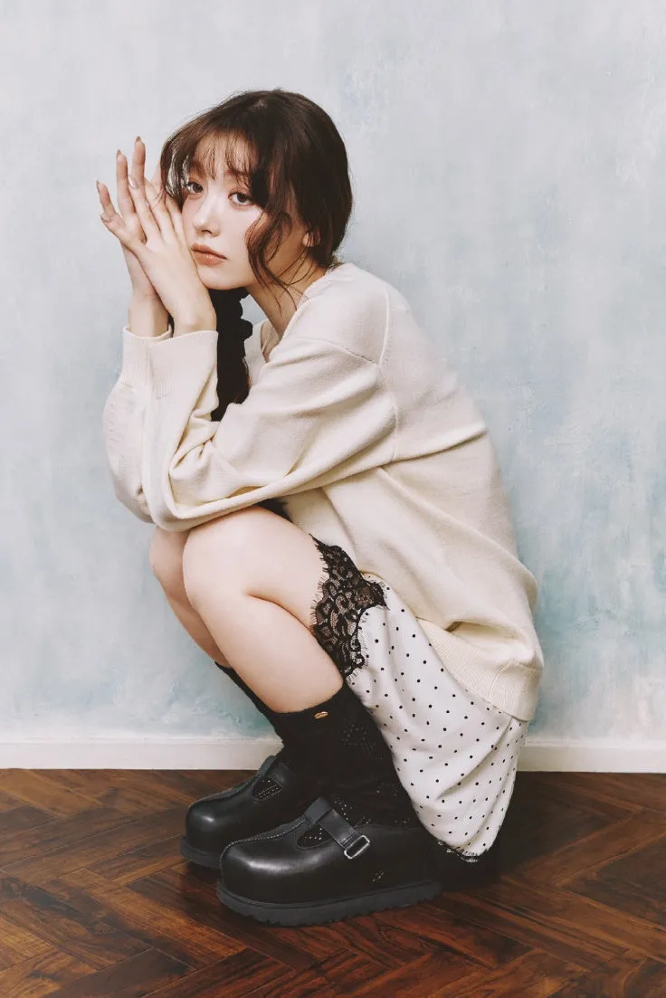 女性がしゃがみこみ、両手を顔の前に持っている写真。